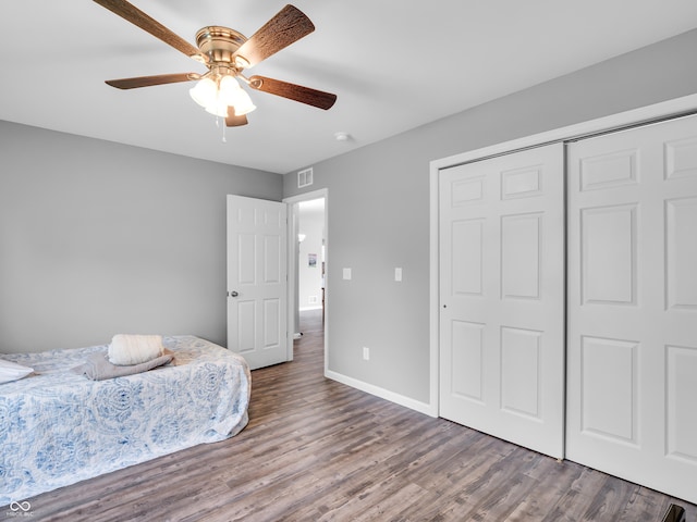 bedroom featuring wood finished floors, visible vents, a closet, and baseboards