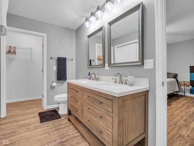 full bath featuring baseboards, wood finished floors, toilet, and a sink