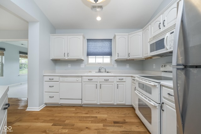 kitchen featuring visible vents, a sink, light countertops, white appliances, and white cabinetry