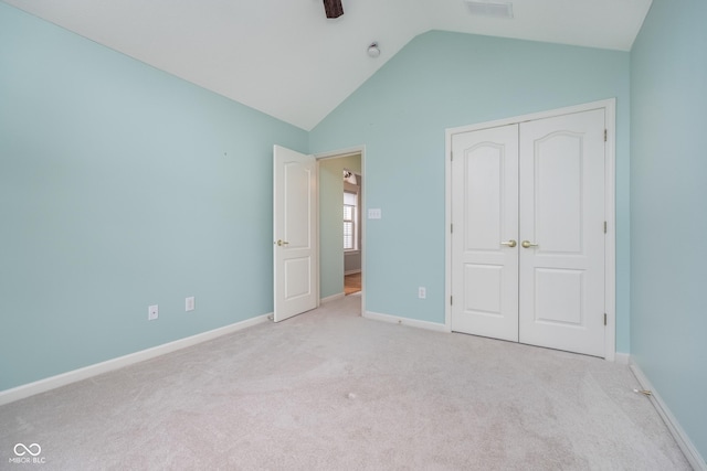 unfurnished bedroom featuring baseboards, a closet, carpet flooring, and lofted ceiling