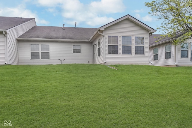 rear view of house featuring a lawn and roof with shingles