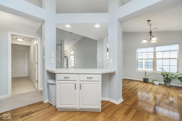 kitchen featuring light countertops, white cabinetry, baseboards, and light wood-style floors