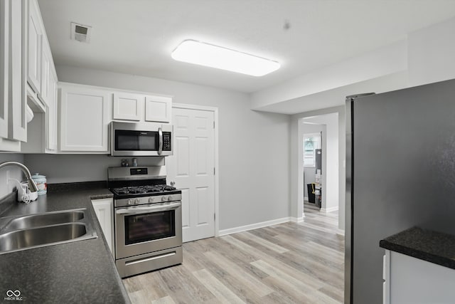 842 Miller Ave, Shelbyville, IN 46176 - kitchen featuring appliances with stainless steel finishes, dark countertops, a sink, white cabinets, and light wood finished floors