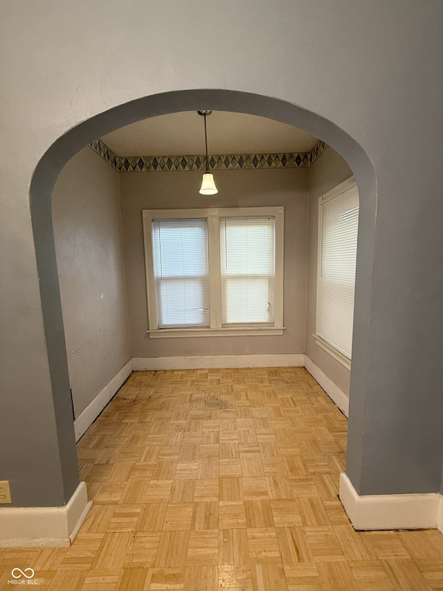 unfurnished dining area featuring baseboards and arched walkways