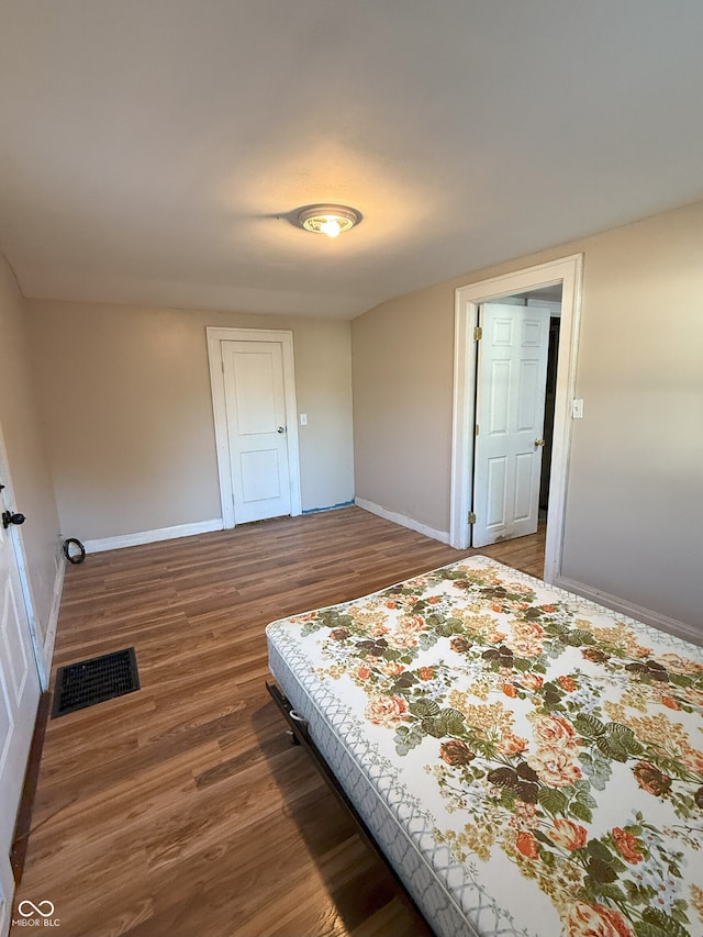 bedroom with visible vents, wood finished floors, and baseboards