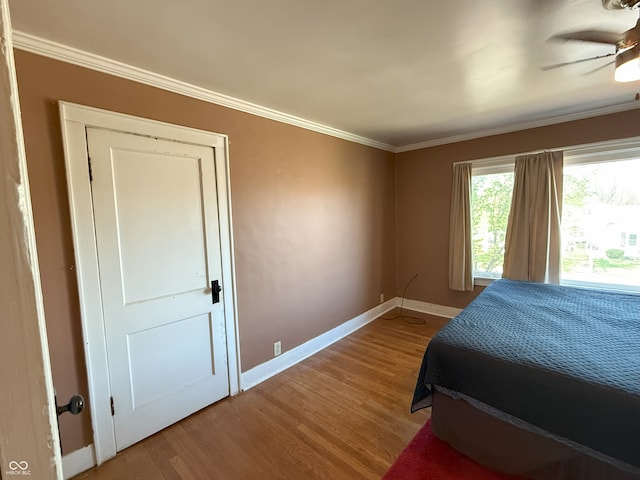 bedroom featuring crown molding, a ceiling fan, wood finished floors, and baseboards