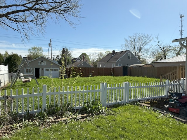 view of yard featuring a garage, fence, and an outdoor structure