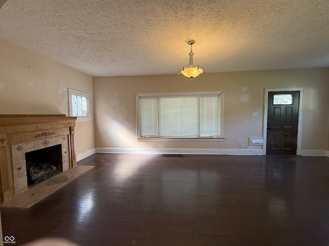 unfurnished living room with baseboards, a fireplace, a textured ceiling, and dark wood-type flooring