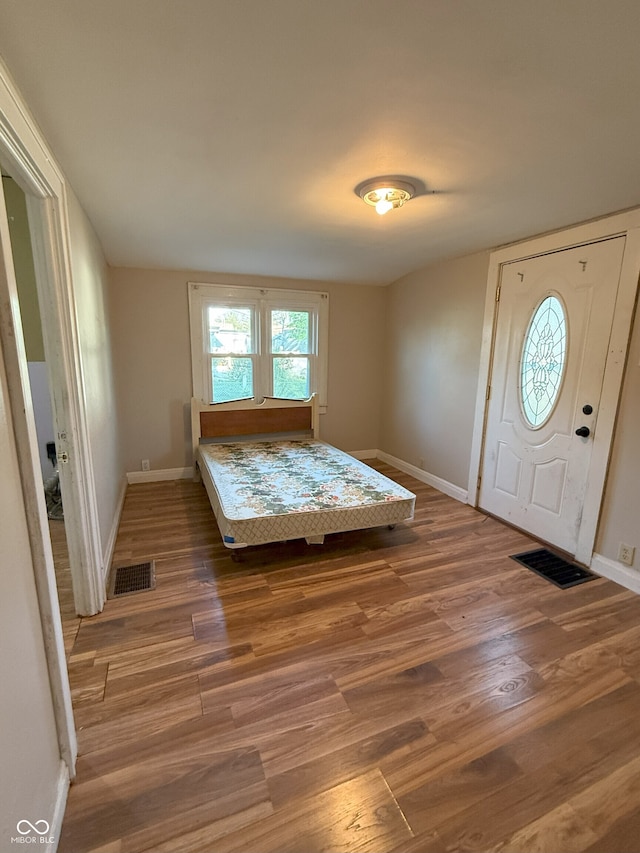 bedroom featuring wood finished floors, visible vents, and baseboards