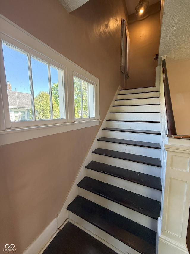 stairway featuring a textured ceiling