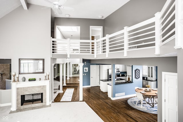 10919 Running Tide Ct, Indianapolis, IN 46236 - living area with high vaulted ceiling, dark wood-style flooring, a ceiling fan, beamed ceiling, and a fireplace