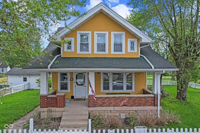 view of front facade with fence, covered porch, roof with shingles, and a front yard