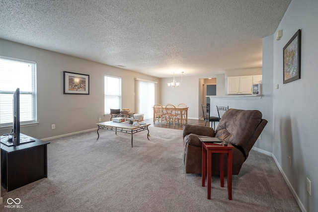 living area featuring carpet flooring, a textured ceiling, and a notable chandelier