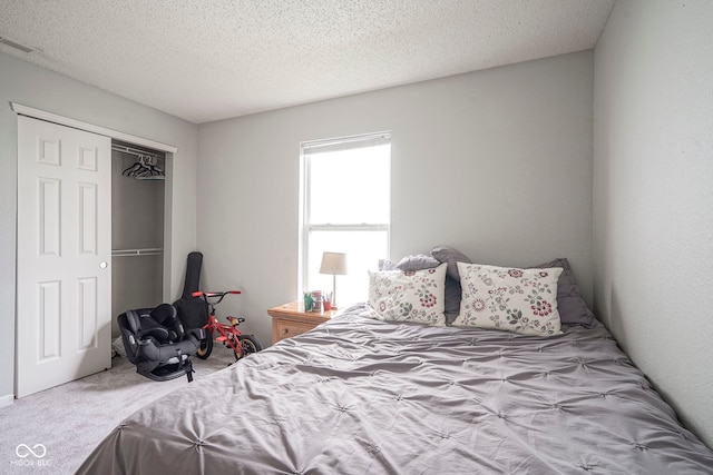 bedroom with a closet, a textured ceiling, carpet, and visible vents