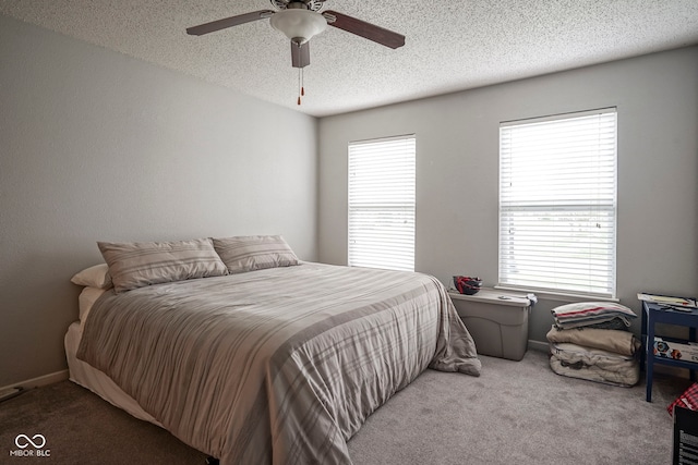 bedroom featuring carpet floors, multiple windows, a ceiling fan, and a textured ceiling