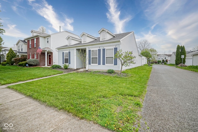 view of front facade with a residential view, driveway, and a front yard