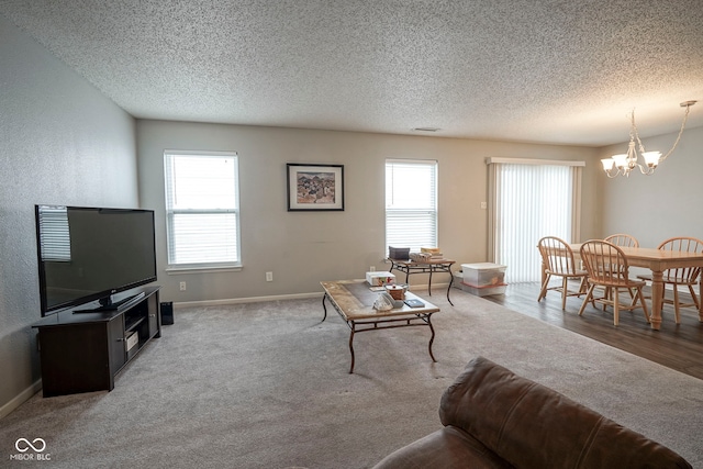 living room featuring an inviting chandelier, baseboards, carpet flooring, and a textured ceiling