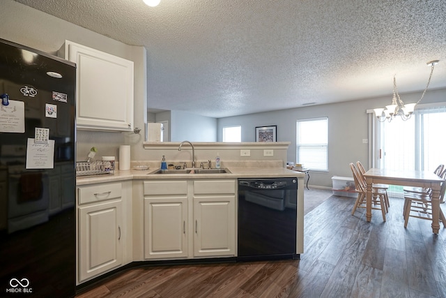 kitchen with a sink, a textured ceiling, a notable chandelier, and black appliances
