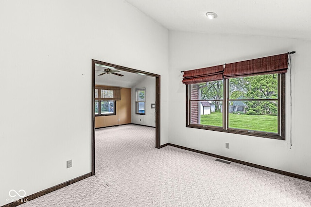 carpeted spare room with vaulted ceiling, baseboards, and a ceiling fan