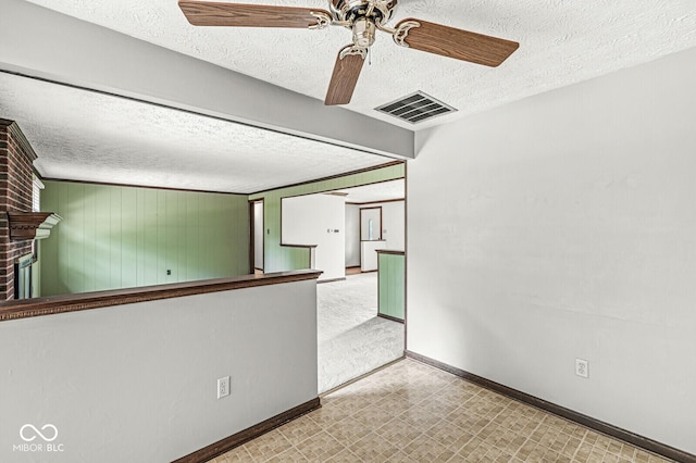 unfurnished room with a textured ceiling, ceiling fan, baseboards, tile patterned floors, and a fireplace