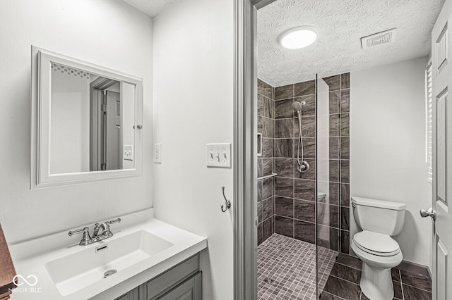 full bathroom with toilet, a stall shower, vanity, and a textured ceiling