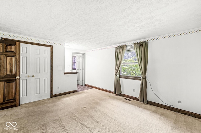 carpeted spare room with a textured ceiling and baseboards