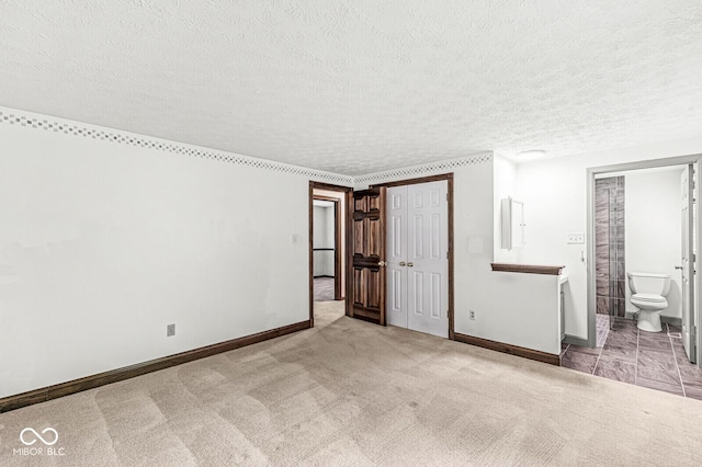 spare room with a textured ceiling, baseboards, and carpet