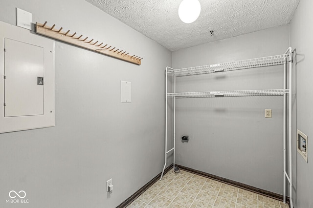 washroom featuring hookup for an electric dryer, a textured ceiling, electric panel, baseboards, and light floors