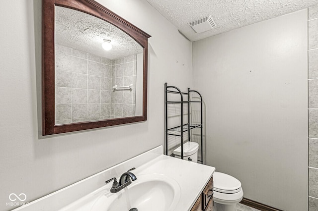 bathroom featuring a textured ceiling, toilet, and vanity