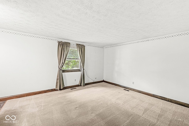 spare room featuring a textured ceiling, carpet, and baseboards