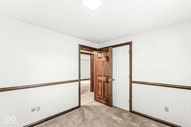 spare room featuring light carpet and a textured ceiling