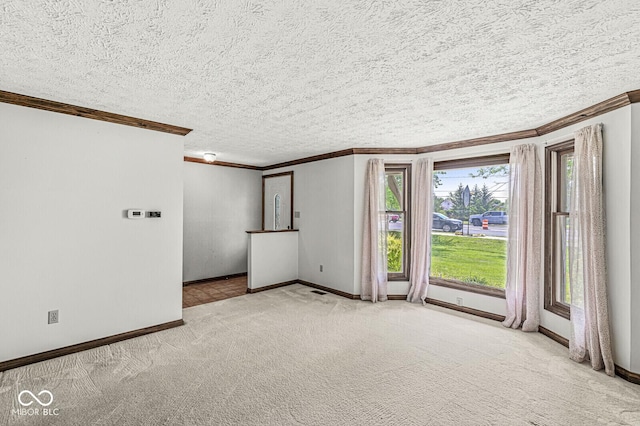 empty room with ornamental molding, baseboards, carpet floors, and a textured ceiling