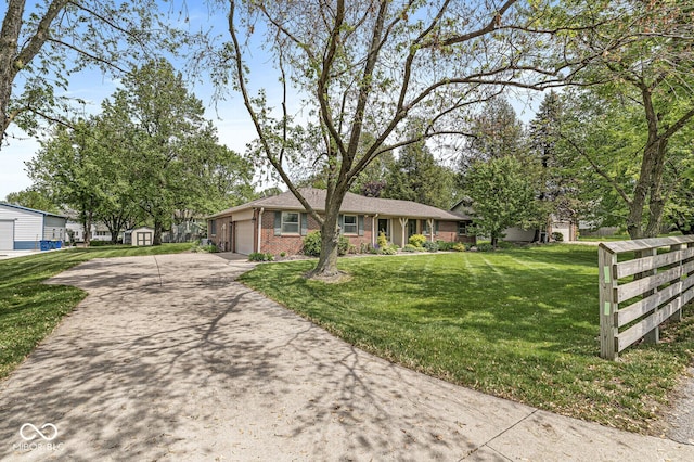 ranch-style house with brick siding, concrete driveway, a front lawn, a garage, and a shed