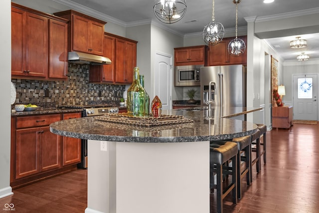 kitchen featuring under cabinet range hood, stainless steel appliances, dark wood-style flooring, and a breakfast bar area