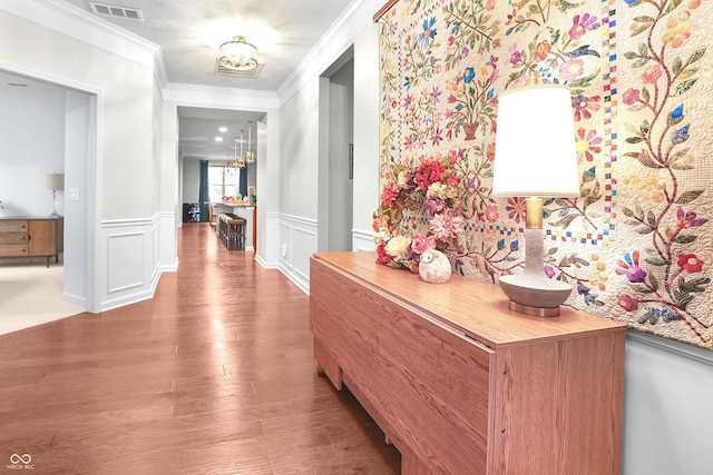 hall with visible vents, wainscoting, crown molding, and wood finished floors