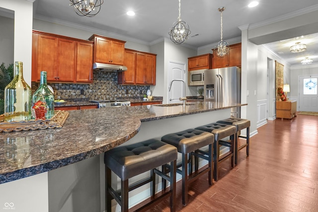 kitchen featuring a breakfast bar area, crown molding, a sink, a chandelier, and stainless steel appliances