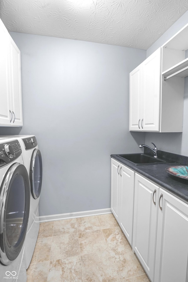 laundry room featuring separate washer and dryer, a sink, cabinet space, and baseboards