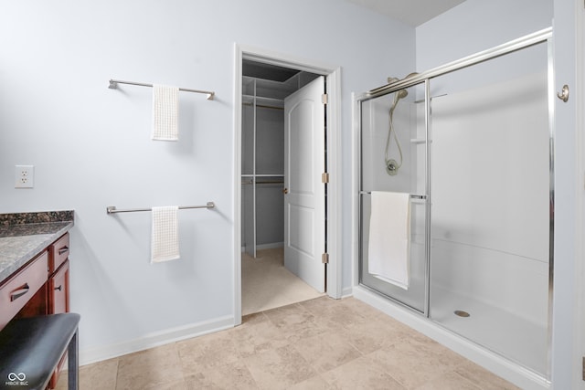 bathroom featuring vanity, a shower stall, and a walk in closet