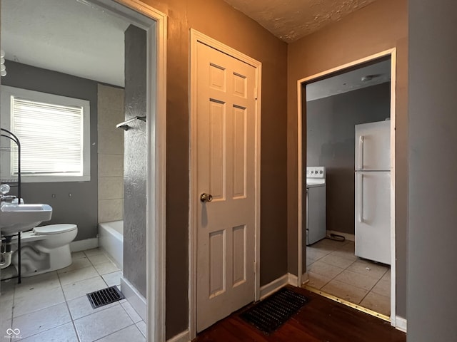 3541 Orchard Ave, Indianapolis, IN 46218 - bathroom featuring visible vents, tile patterned floors, baseboards, toilet, and washer / dryer