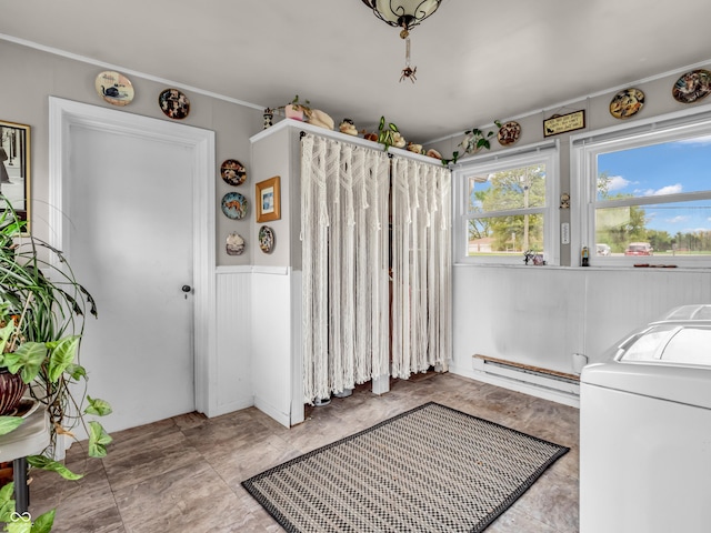 clothes washing area with a wainscoted wall, washer / clothes dryer, and a baseboard heating unit