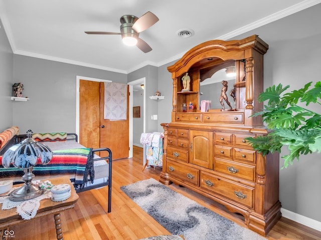 bedroom featuring ceiling fan, visible vents, baseboards, light wood-type flooring, and ornamental molding