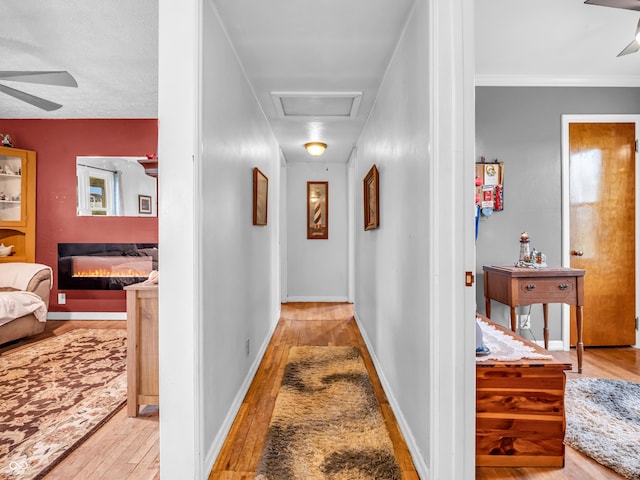 hall featuring baseboards, attic access, and wood-type flooring