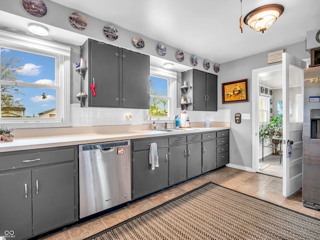 kitchen featuring stainless steel dishwasher, open shelves, a sink, light countertops, and gray cabinets