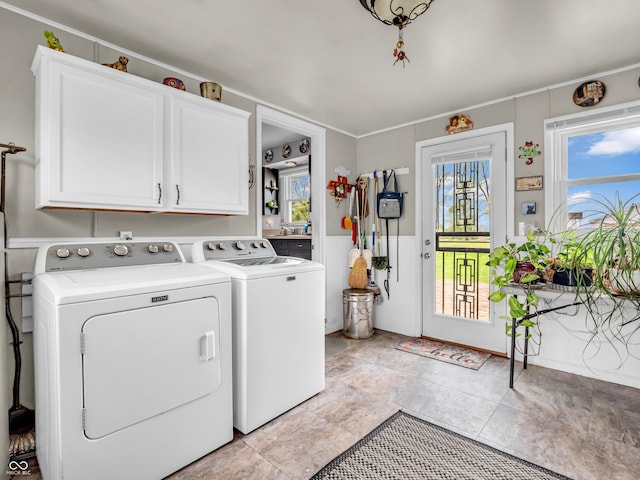 laundry area featuring a wainscoted wall, cabinet space, and washer and clothes dryer