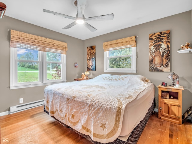 bedroom featuring baseboards, wood finished floors, ceiling fan, and a baseboard radiator