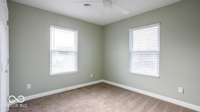 carpeted spare room with plenty of natural light, a ceiling fan, and baseboards