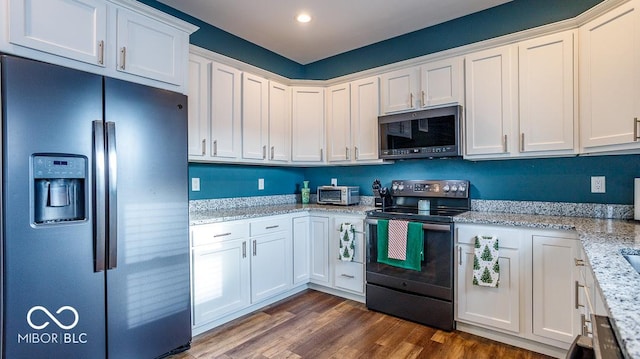 kitchen with black electric range oven, stainless steel microwave, white cabinets, and refrigerator with ice dispenser
