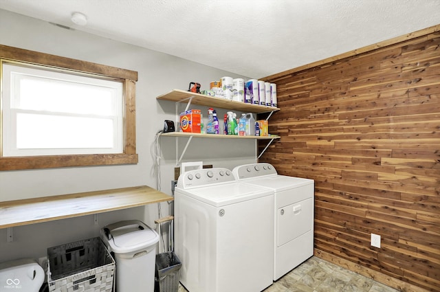 clothes washing area featuring wooden walls, laundry area, and washer and clothes dryer