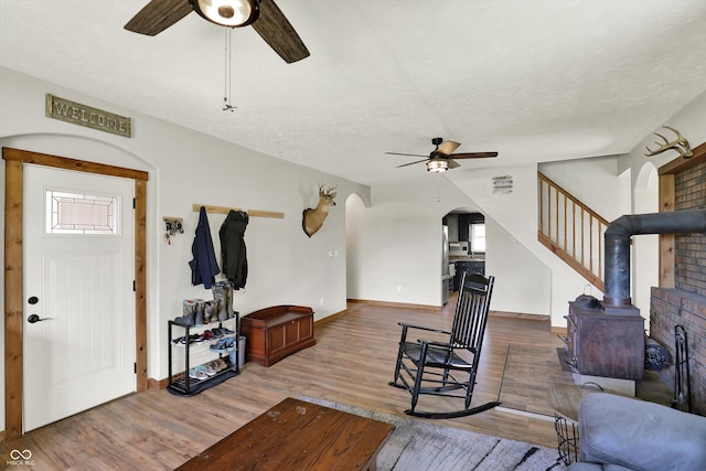 living area with baseboards, arched walkways, ceiling fan, and wood finished floors