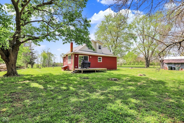 back of property with a lawn, a chimney, and a deck